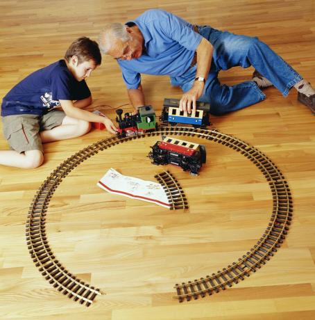Vnuk a dědeček si hrají s železnicí