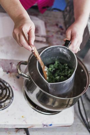 Žena míchá džbán horkého sójového vosku, aby si připravila ručně vyráběné svíčky