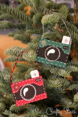 Adornos de fieltro con forma de cámara colgando de un árbol de Navidad.