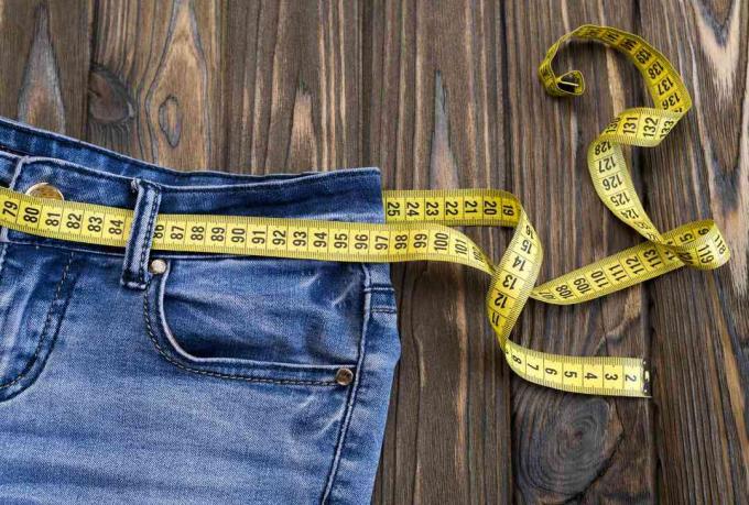 jeans, centímetro em um fundo de madeira. dieta. cintura