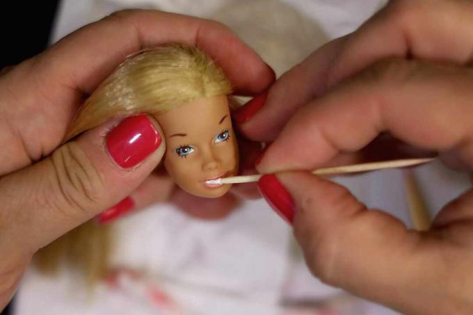 Alguém pintando novos recursos na cabeça da boneca Barbie