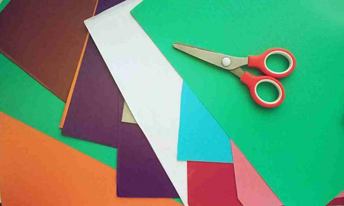 Høy vinkelvisning av flerfargede papirer og saks på bordet
