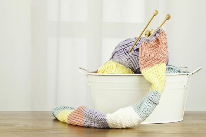 Cachecol tricotado à mão e fios em um balde.