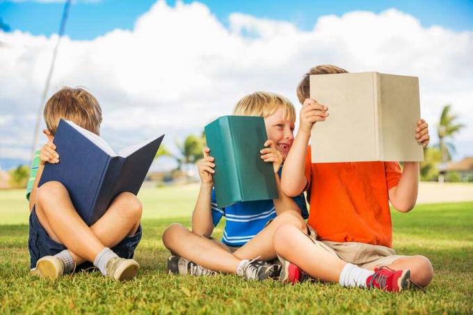 Grupa szczęśliwych dzieci czytających książki na zewnątrz, przyjaźń i nauka