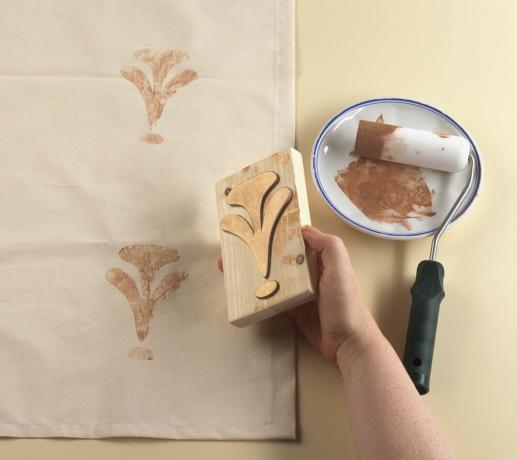 Estampagem da borda da cortina usando bloco de impressão de madeira, rolo de pintura próximo, close-up