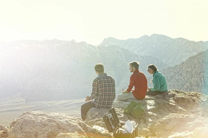 Kolme ystävää istuu vuoren huipulla