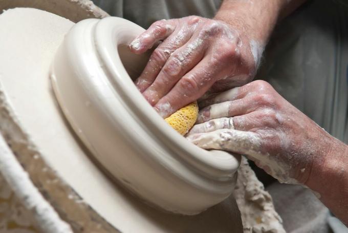 Potter pomocí houby tvaruje misku na hrnčířském kruhu.