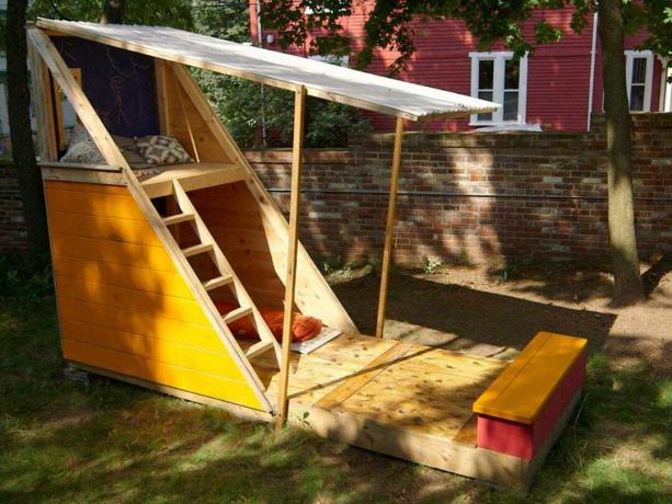 Une maison de jeu avec des escaliers, un banc et un toit rabattable