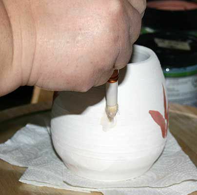 Muž nanášení voskového odporu nad hliněnou nádobu