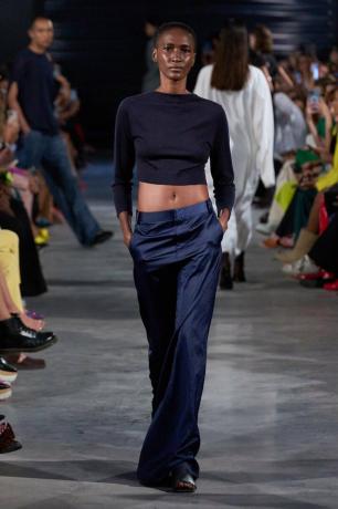 מגמות אופנה אביב קיץ 2023: דוגמנית לובשת מכנס נייבי וחולצה שחורה עם שרוולים ארוכים על המסלול של טיבי אביב קיץ 2023