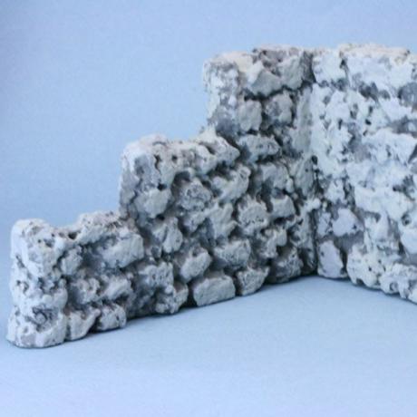 Uma parede de pedra falsa feita de placa de isopor com três tons de cinza aplicados para imitar a pedra.