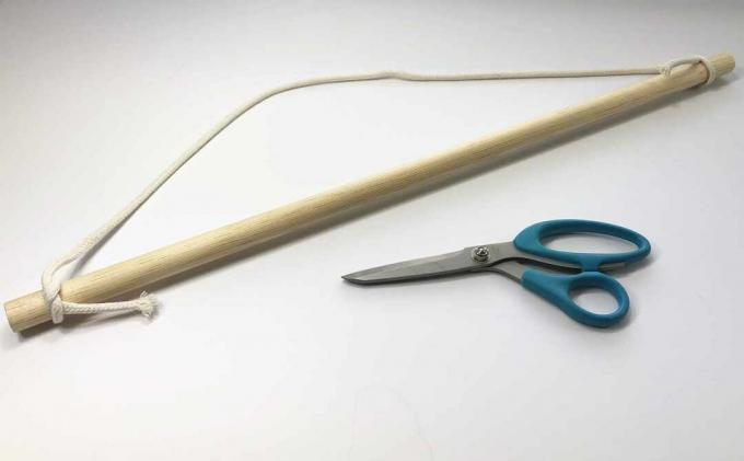 Šňůra macrame připevněná k dřevěné hmoždince s nůžkami vedle ní