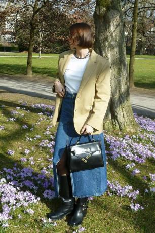 משפיענית אופנה סקנדי לובשת בלייזר, חצאית ג'ינס ומגפיים