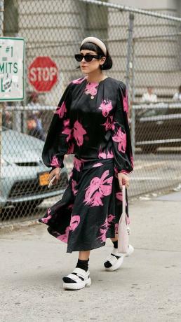 Niujorko mados savaitės gatvės stiliaus tendencijos 2019 m.: rožinė ir juoda gėlių suknelė su galvos apdangalu ir plokščiomis formomis