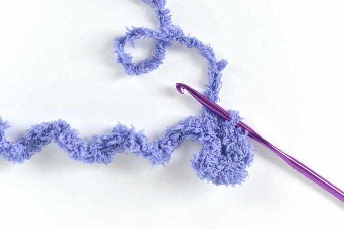 Hilo morado suave alrededor de la aguja de crochet