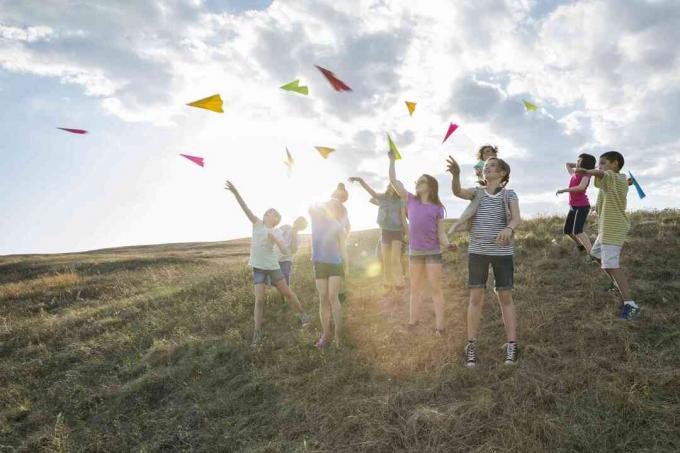 Gruppe av barn utendørs som kaster papirfly