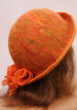 En oransje, våt filthatt på en kvinnes hode