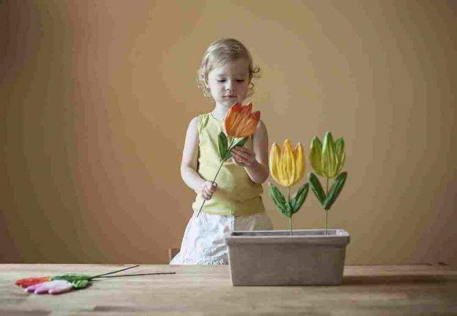 dívka si hraje s papírovými květinami