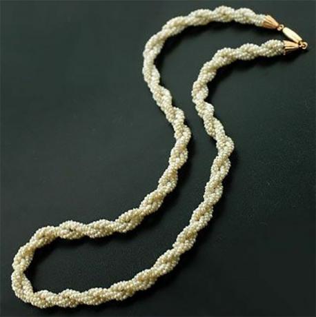Weiße Bayadère-Halskette mit Verschluss auf schwarzem Hintergrund.