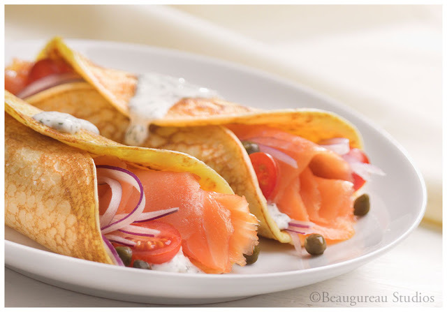Salmon segar dipotong dan digulung menjadi crepes, disajikan dengan tomat ceri dan bawang bombay 