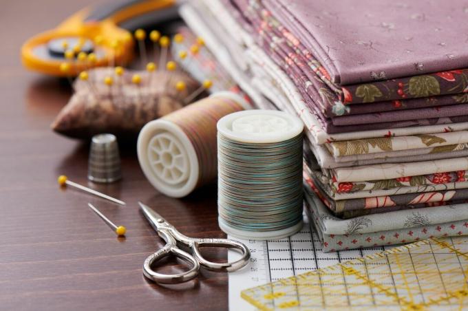 Pile de tissu pour patchwork sur tapis artisanal, accessoires de couture sur surface en bois