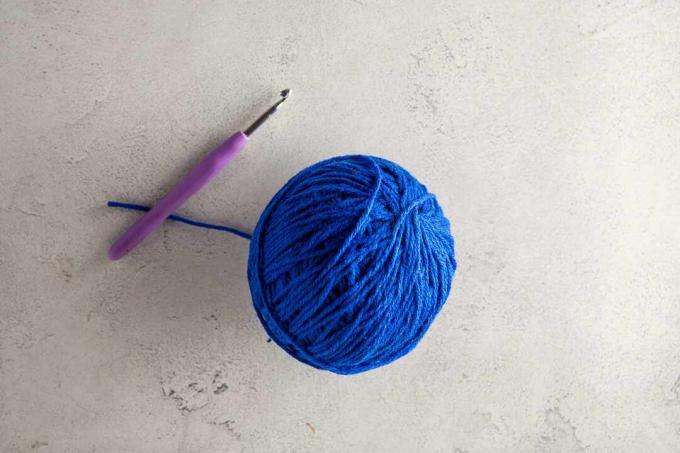 Une pelote de laine bleue et un crochet.
